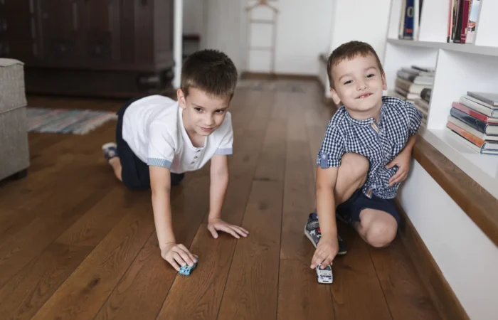 two-boys-playing-with-car-toys-hardwood-floor